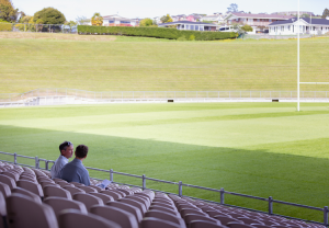 Two men chat in grandstand at stadium